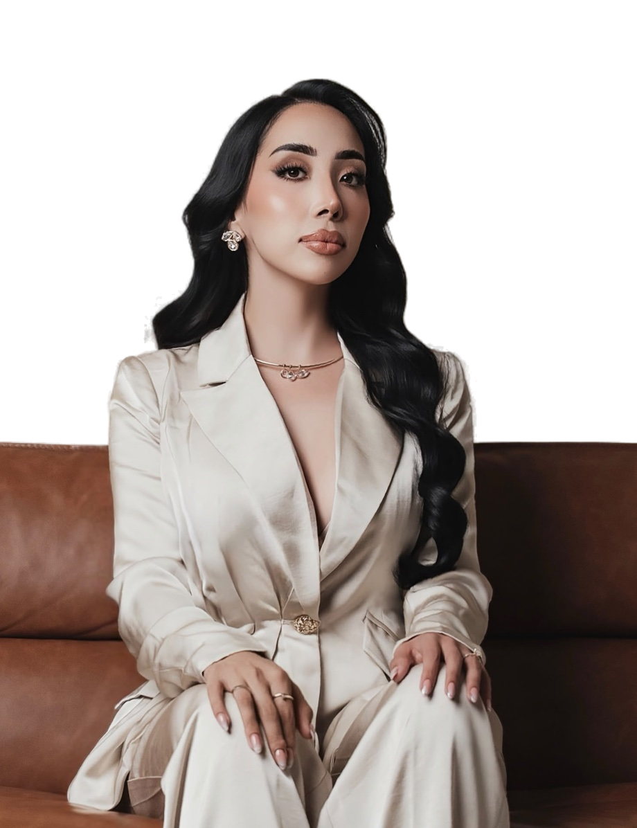 Grecia Lopez Torrez sentada de frente en un sofá de piel café, con traje color marfil y las manos sobre las rodillas.